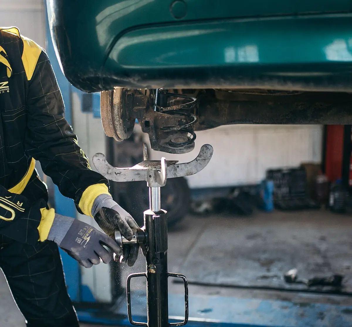 Mecánico trabajando bajo un coche elevado en un taller